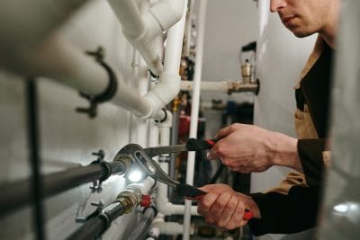 Technician inspecting commercial plumbing pipes in Irvine
